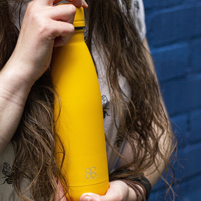 Lady with long brown hair holding a  yellow water bottleow re