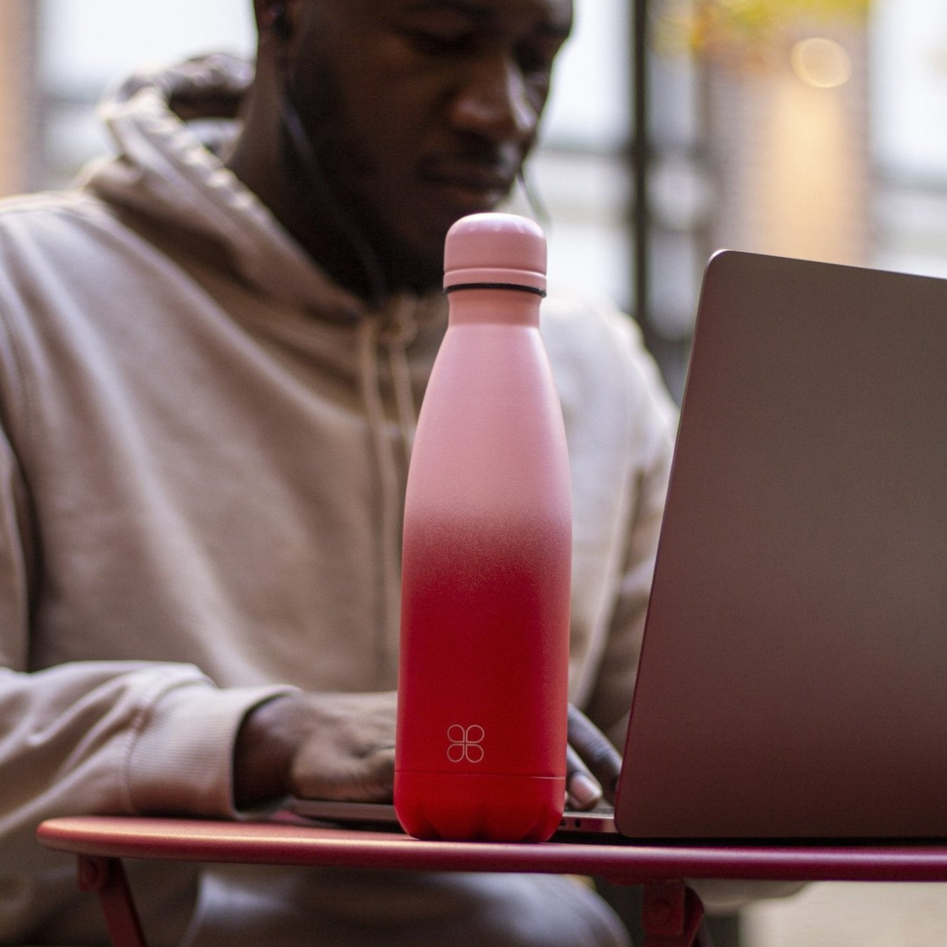 Man concentrates on an apple laptop with a red and pink stainless steel bottle 500ml